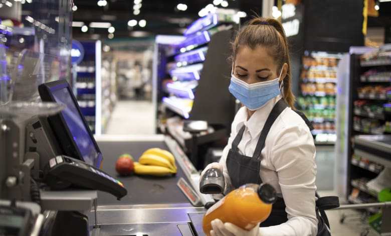 cashier in supermarket wearing mask and gloves fully protected against corona virus - Diario Resumen de la región